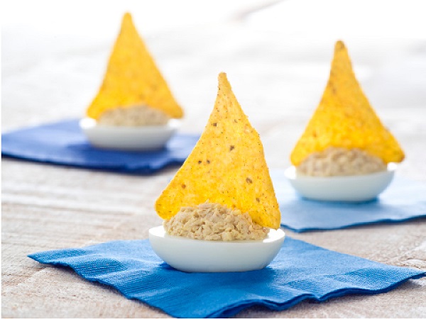 Boiled eggs, cut in half filled with tuna and a nacho chip place on top