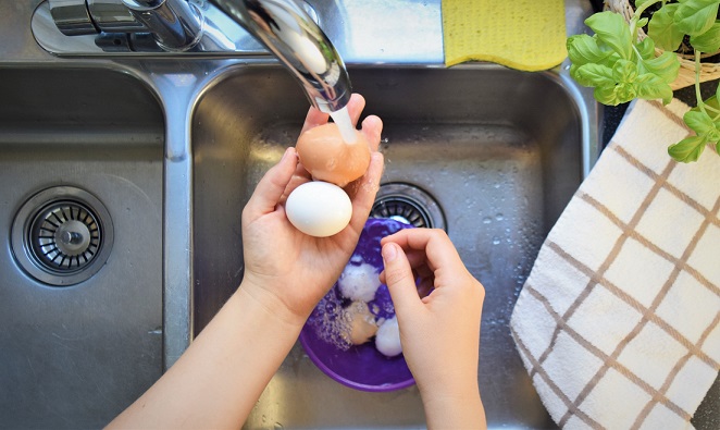 Eggs in a bowl being rinsed in a sink during washing process